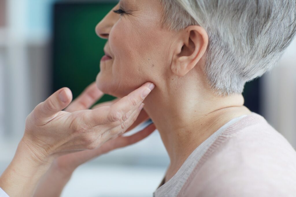 Doctor Examining Neck of Senior Woman