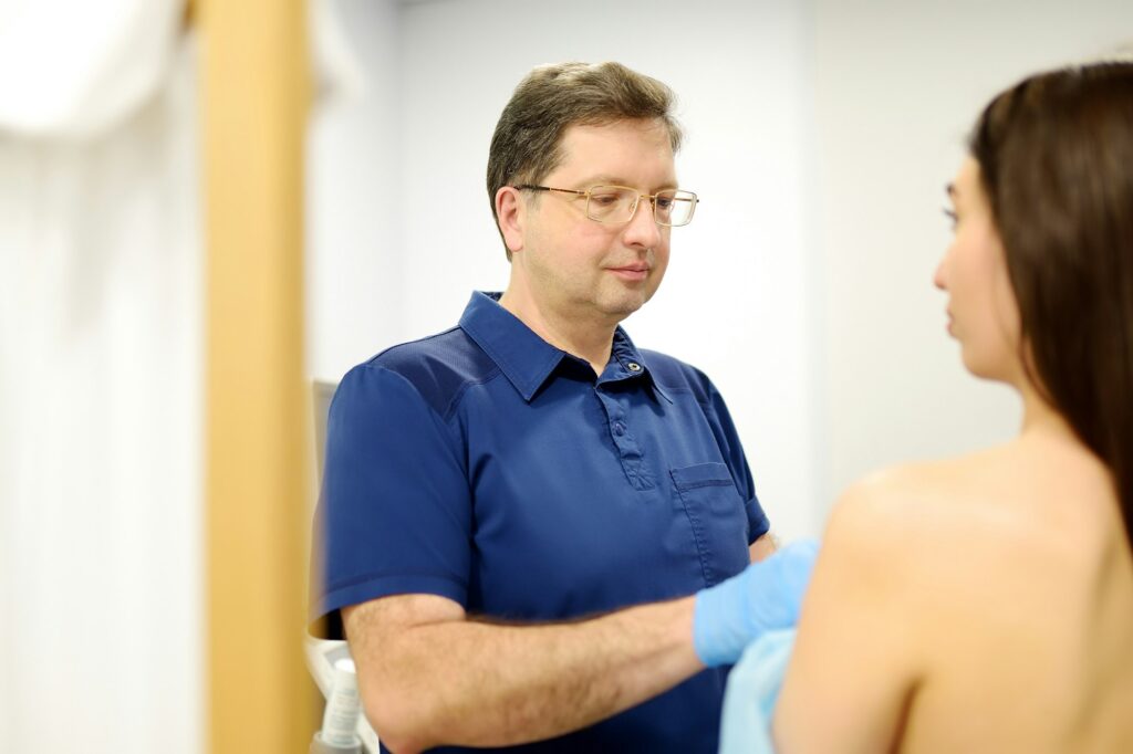 Doctor mammologist examines woman breasts.