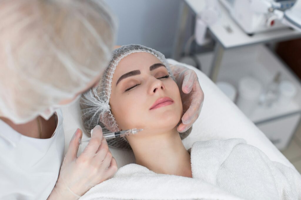 Hands of cosmetologist making injection in face, lips.