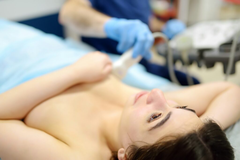 Mammologist doctor examines a woman breasts and lymph nodes using ultrasound.