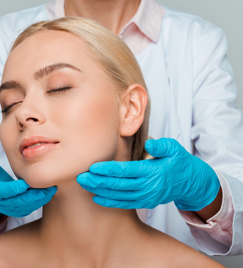 cropped view of beautician in blue latex gloves touching neck of naked woman with closed eyes