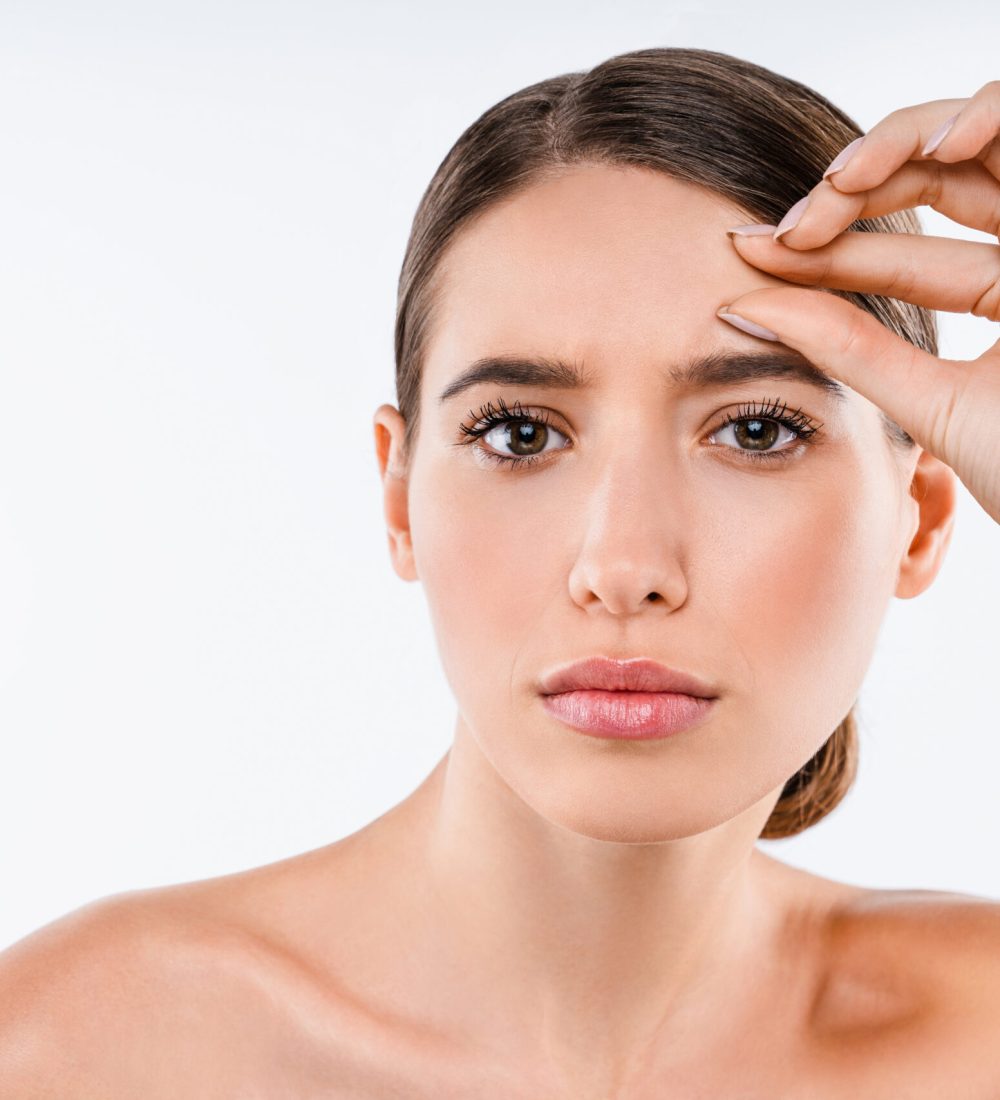 Portrait of not happy young brunette half naked woman touching her face isolated over white background